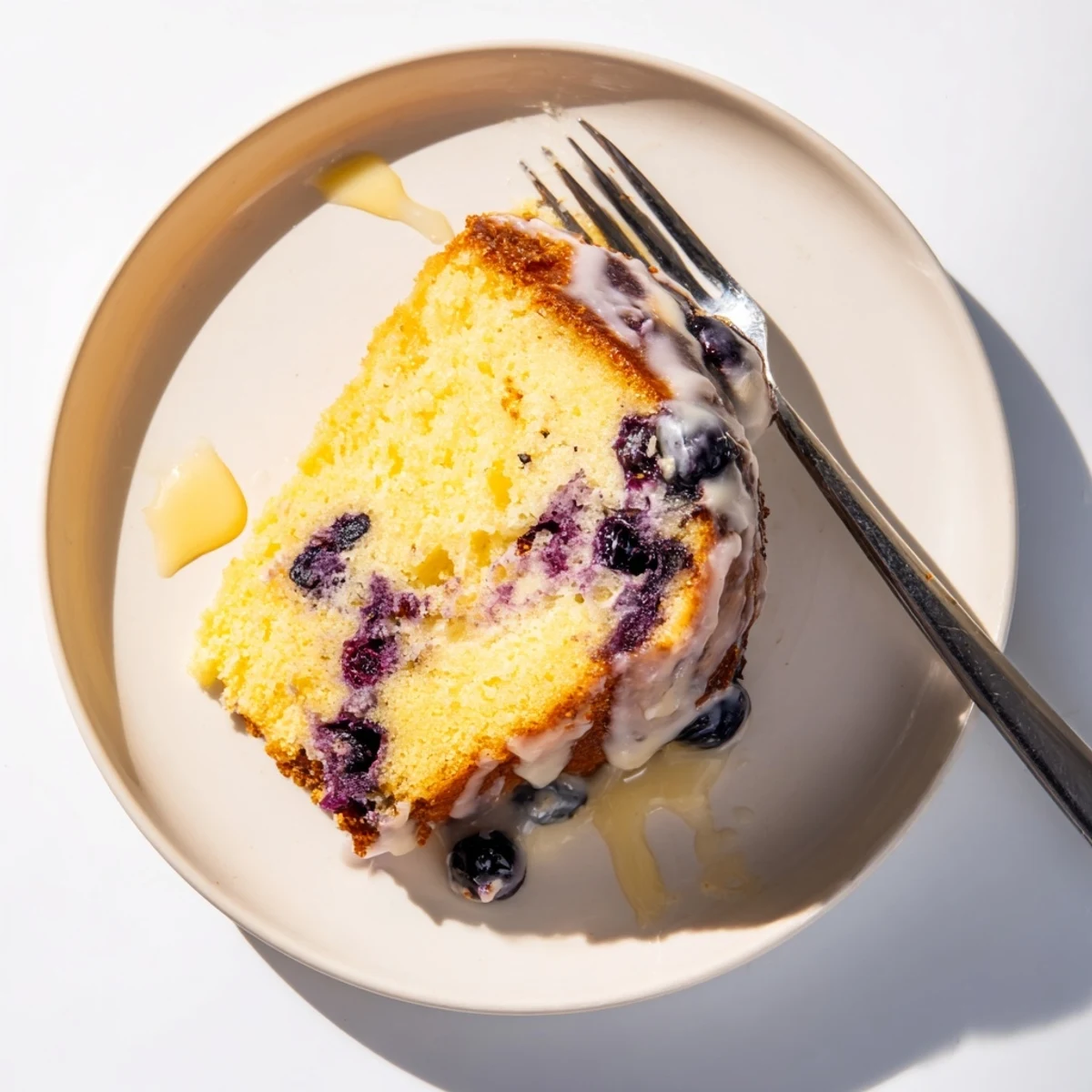 Moist lemon blueberry cake drizzled with white glaze and dotted with fresh blueberries