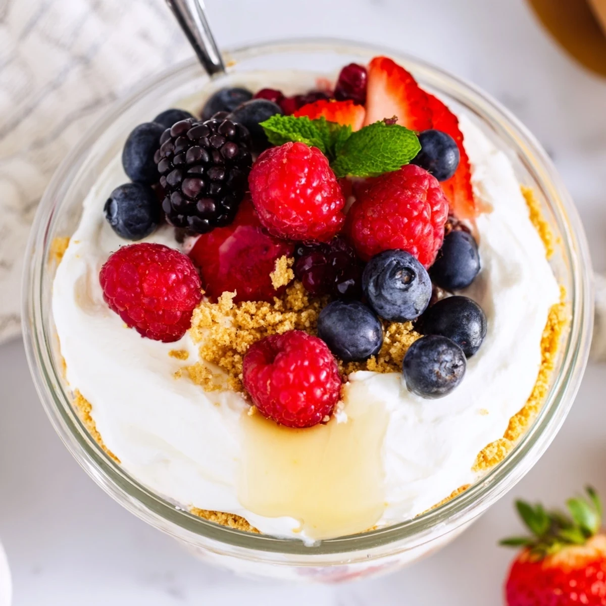 Creamy no bake berry cheesecake bowls topped with fresh mixed berries and crunchy graham cracker crust