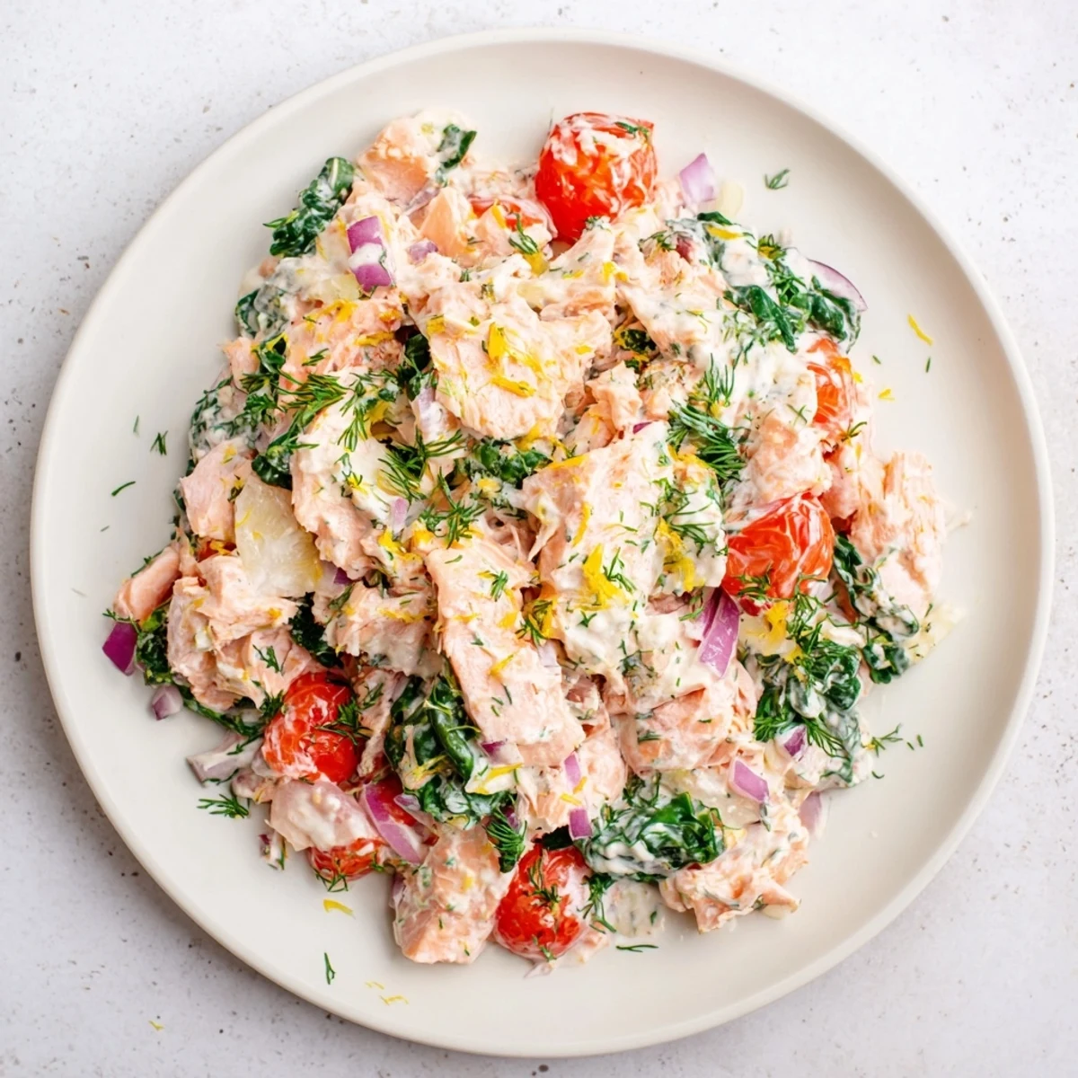 Creamy leftover salmon recipe with spinach, tomatoes, and a tangy lemon dill yogurt sauce.