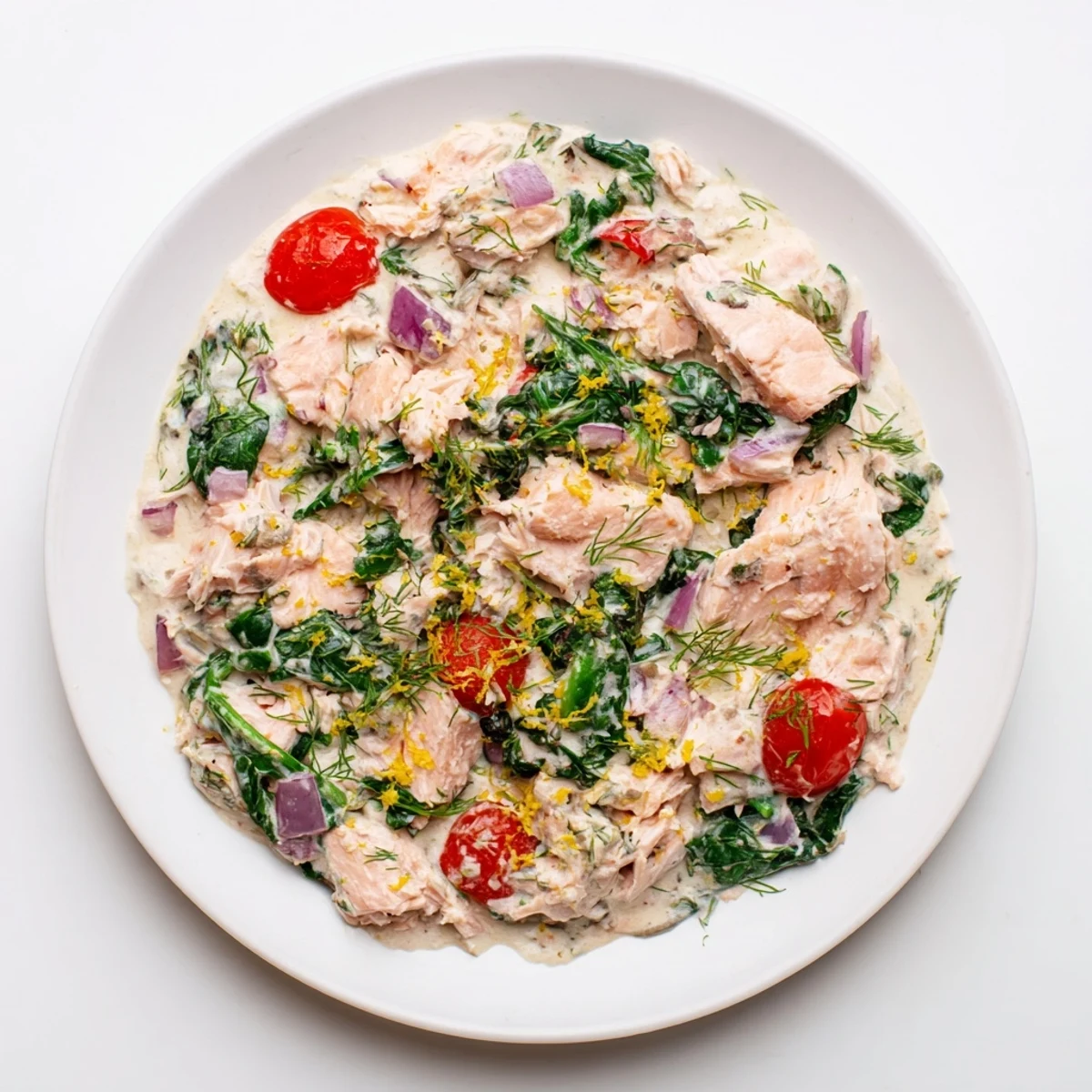 Savory leftover salmon recipe featuring flaked fish in a rich white sauce with vegetables.